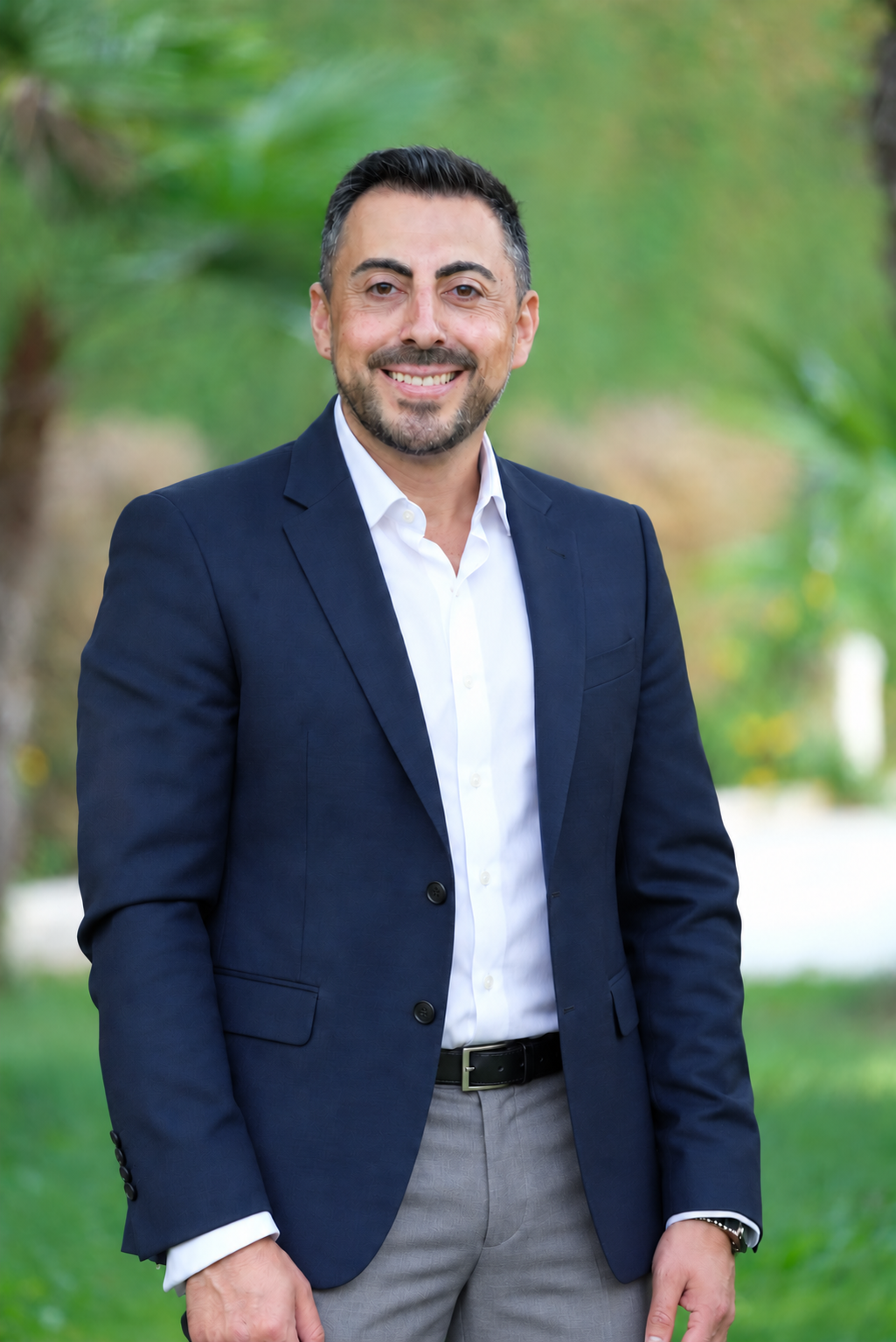 Portrait d’Ali Darwiche en costume, souriant dans un jardin